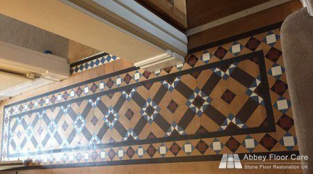 Heavily soiled Victorian hallway tiles with faded colours and obscured geometric patterns