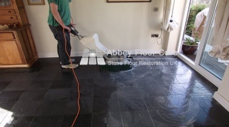 Slate floor tiles during cleaning with visible soil and uneven colour