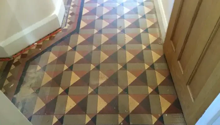 Worn Minton tile floor in Tutbury showing heavy soiling and dulled surface before restoration